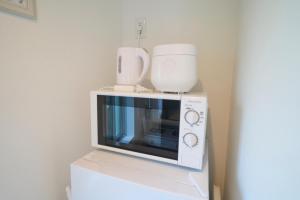 a white microwave sitting on top of a refrigerator at Koeda House in Tokyo