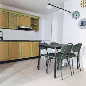 a kitchen with a table and green chairs at B&B L'alba Nel Golfo in Castelsardo