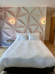 a large white bed in a room with a wall at Les Rubys, spas privatifs in Tarcenay