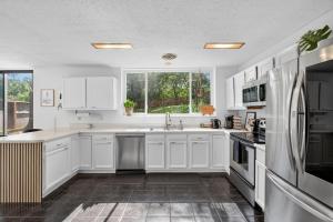 a kitchen with white cabinets and a large window at The Palms Mirage House home in Millman