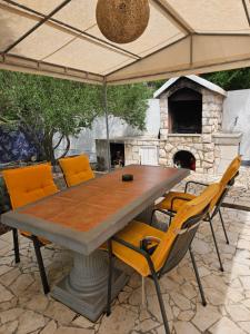 Ein Tisch und Stühle unter einem Sonnenschirm mit einem Steinofen in der Unterkunft Kuća za odmor Timón in Barbat na Rabu