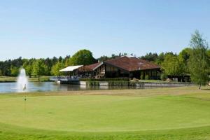 a golf course with a house and a pond with a fountain at De Orangerie in Loenen