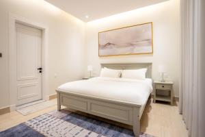 a white bedroom with a bed and a painting on the wall at Riyadh Comfort Stay - Luxury الملقا Almalqa in Riyadh