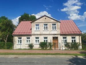 ein altes weißes Haus mit rotem Dach in der Unterkunft K's Studio in Kuldīga