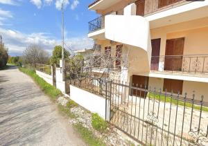 a building with a fence next to a street at Antonia's Apartments-Traditional house next to the beach in Valimítika +12 photos