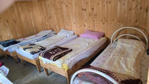 three beds in a room with wooden walls at Guest House Balcina in Kolgecaj