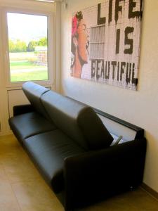 a black leather couch in a room with a window at Ferienwohnung Am Ziegelbach in Hechingen