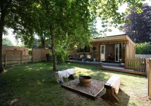 a backyard with a small wooden house with a tree at Copper Beech Lodge with Hot Tub, Games Room, Fire Pit in Toppesfield