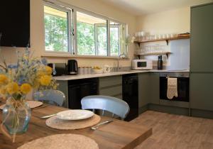 a kitchen with a wooden table with a vase of flowers at Copper Beech Lodge with Hot Tub, Games Room, Fire Pit in Toppesfield