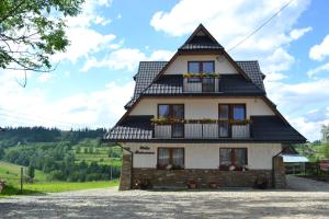 una casa con techo negro y flores en las ventanas en Willa Bukowina, en Bukowina Tatrzańska