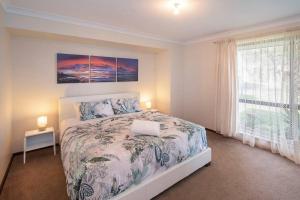a white bedroom with a bed and a window at Duke Street Hideaway in Busselton