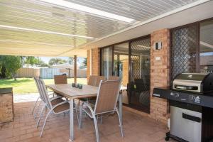 a patio with a table and chairs and a grill at Duke Street Hideaway in Busselton