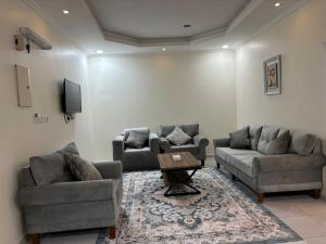 a living room with two couches and a table at Osis Ghin served apartment in Yanbu