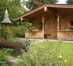a wooden house with a porch and a garden at Pension Wolfsegg in Kirchberg in Tirol