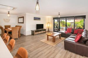 a living room with a couch and a television and a table at Just Chillin- Pool, 2km to beach in Broadwater