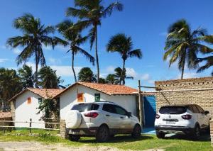 two cars parked in front of a house with palm trees at Cabanas Caraúbas - frente para o mar, ar & Tv in Maxaranguape +67 photos