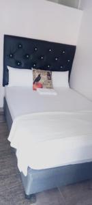 a white bed with a black headboard and white pillows at Master Palace Guest House - Randfontien in Randfontein