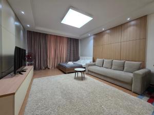 Una sala de estar con un sofá y un televisor. en 417 Luxury Апартаменты 2х комн кв с 2мя кроватями и раскладным диваном возле посольства США, Хайвилл, en Astana