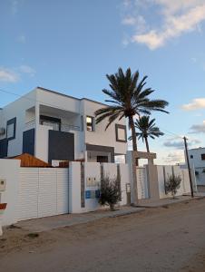 a white house with a fence and a palm tree at اقامة بيرم Résidence Bayrem in Houmt Souk
