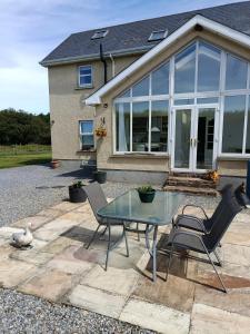 a glass table and chairs in front of a house at The Feathered Nest Apartment at The Cracked Hen in Gorey
