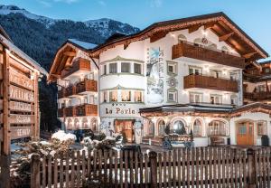 een huis in de bergen met een hek bij Hotel La Perla Wellness & Beauty in Canazei