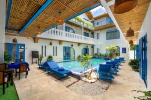 a pool with blue lounge chairs in a courtyard at The Linh Coastline Villa in Hoi An