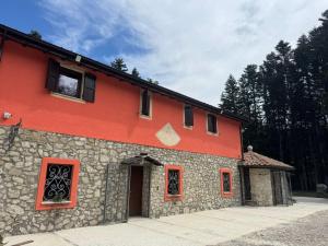 a red building with red windows and a door at Malga Filippi 1241 in Polino +13 photos