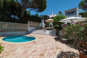 a backyard with a swimming pool and an umbrella at Vila Antic in Almancil