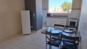 a kitchen with a table and chairs and a refrigerator at Rivello Apart Hotel in Sete Lagoas