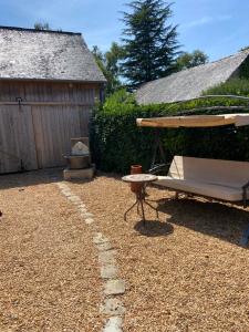 un patio con una panchina, un ombrellone e un tavolo di Sunflower Cottage a Genneteil