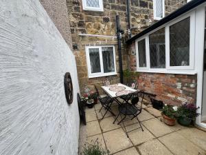 a patio with a table and chairs in front of a brick building at Guisborough 3-Bed, with parking, Walk to Pubs, Shops & Trails in Guisborough