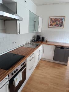 a kitchen with white cabinets and a wooden floor at Ferienwohnung am Kurwald, Nähe Kliniken, 88qm, Parkplatz in Bad Lippspringe