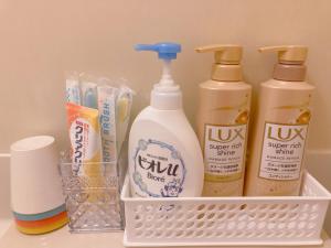 uma cesta branca com quatro garrafas de detergente e pasta de dente em Shinjuku House-1 em Tóquio
