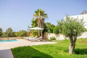 a patio with an umbrella and chairs next to a pool at Rent Your Luxury 2 Bedroom Villa, Ibiza Villa 1025 in Talamanca