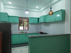 a green kitchen with green cabinets and a window at Pooranam Vacation Home in Jaffna