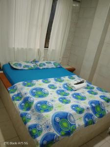 a bed with a blue and white comforter at Hospedaje el balcon suite in Villavicencio