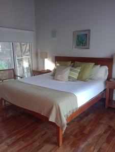 a bedroom with a large bed with white sheets and green pillows at Bosque de Ciruelos in Carilo +17 photos