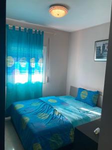 a bedroom with a blue bed and a window at Coastal Elegance in Martil