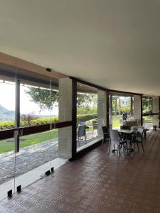 Un comedor con mesa y sillas y ventanas. en The Green Nest - pool & lake view, en Costermano