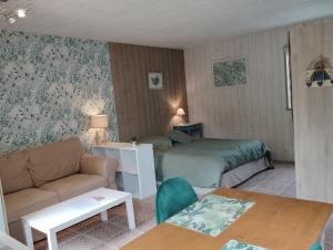 a bedroom with a bed and a couch and a table at Au p'tit jardin in Saint-Sylvestre-de-Cormeilles