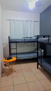 ein Zimmer mit drei Etagenbetten und einem Tisch in der Unterkunft Casa Vila Santa Cecília - No Centro da Cidade in Volta Redonda