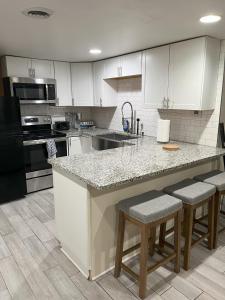 a kitchen with white cabinets and a counter with stools at Ripple Avenue Suites Suite B in Indianapolis