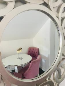 a mirror with a table and purple chairs in a room at Apartman Maslina in Kosjerić