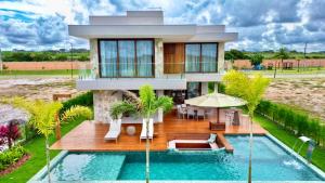 a house with a swimming pool in front of it at Casa com Vista MAR e LAGO em Alphaville Guarajuba in Barra de Jacuípe
