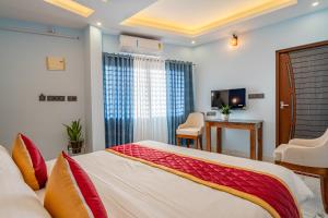 a bedroom with a bed and a desk and a television at AIRNEST Airport Residency in Nedumbassery