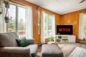 a living room with a tv and a couch at Chalet Oh Deer ! Spa et bois pour feu inclus in Entrelacs