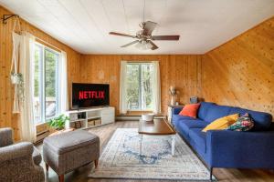 a living room with a blue couch and a tv at Chalet Oh Deer ! Spa et bois pour feu inclus in Entrelacs