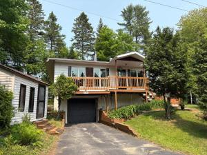 a house with a large deck on a driveway at Chalet Oh Deer ! Spa et bois pour feu inclus in Entrelacs
