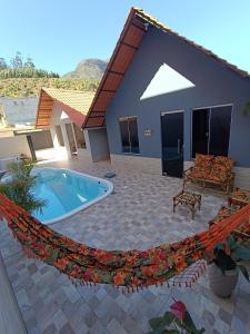 a hammock in front of a house with a pool at Chalé Montanhez in Alto Caparao