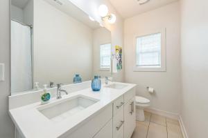 a white bathroom with a sink and a toilet at 4BR Queen City Base Minutes to Stadium & NoDa in Charlotte +18 photos